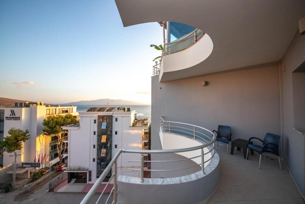 Un bâtiment moderne doté d’un balcon incurvé qui offre une vue sur le paysage urbain et la mer.