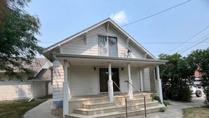 Una casa a un piano con veranda, garage e un piccolo giardino antistante.