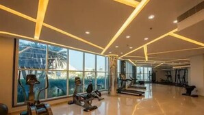 Ein modernes Fitnessstudio mit Trainingsgeräten, großen Fenstern und einem glatten Boden.