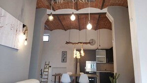 Un espace repas doté d’un plafond rustique, de luminaires suspendus et offrant une vue sur la cuisine.