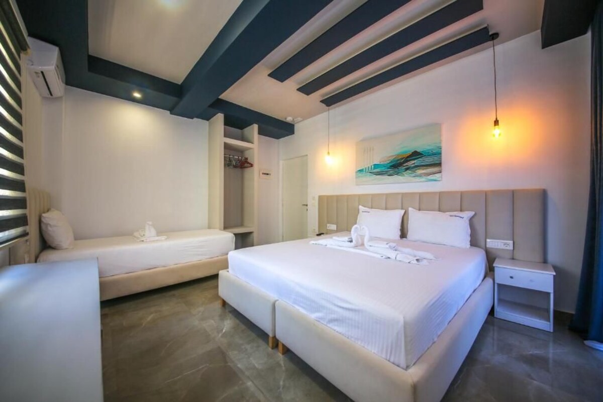 A hotel room with a large bed, a smaller bed, a wardrobe, and a painting on the wall.