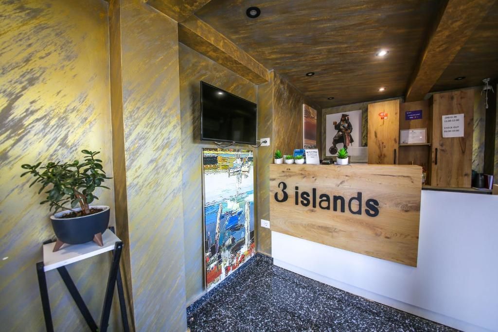Un área de recepción con un mostrador de madera, un televisor montado en la pared y un letrero que dice '3 islas'.