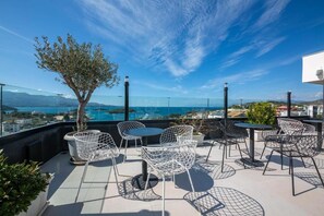 A rooftop terrace with outdoor seating, a view of the sea, and a clear sky. - Rumani 3 Islands Hotel (Ksamil)
