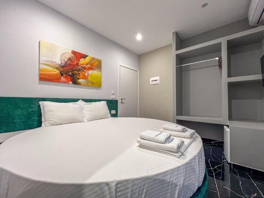 A hotel room with a large bed, a wardrobe, and a painting on the wall.