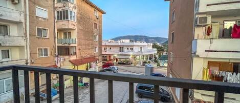 Una strada residenziale con edifici a più piani, un balcone visibile e auto parcheggiate.