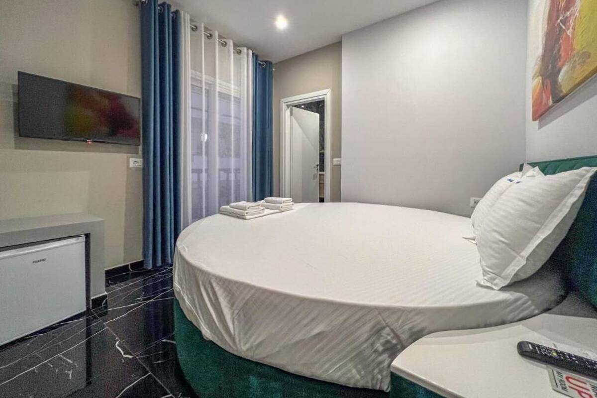 Una habitación de hotel con cama, televisor, escritorio y puerta de baño.