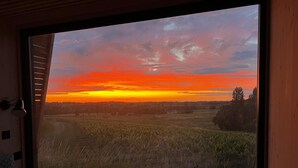 Ein Fenster mit Blick auf einen Sonnenuntergang über einem Feld.