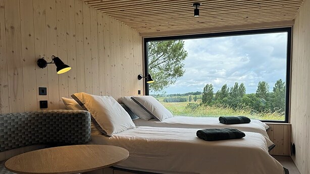 Ein Schlafzimmer mit einem Bett, einer Couch, einem Tisch und einem großen Fenster mit Blick ins Freie.