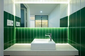 A modern bathroom with a rectangular sink, green tiled walls, and a visible door in the background. - Q Hotel & Apartment Han Market Da Nang (Da Nang)