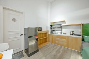 A compact kitchen with a refrigerator, microwave, and wooden cabinets. - Q Hotel & Apartment Han Market Da Nang (Da Nang)