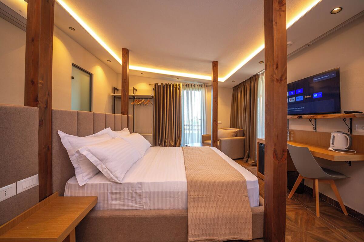 A hotel room with a bed, a desk, a chair, a television, and a window with curtains.