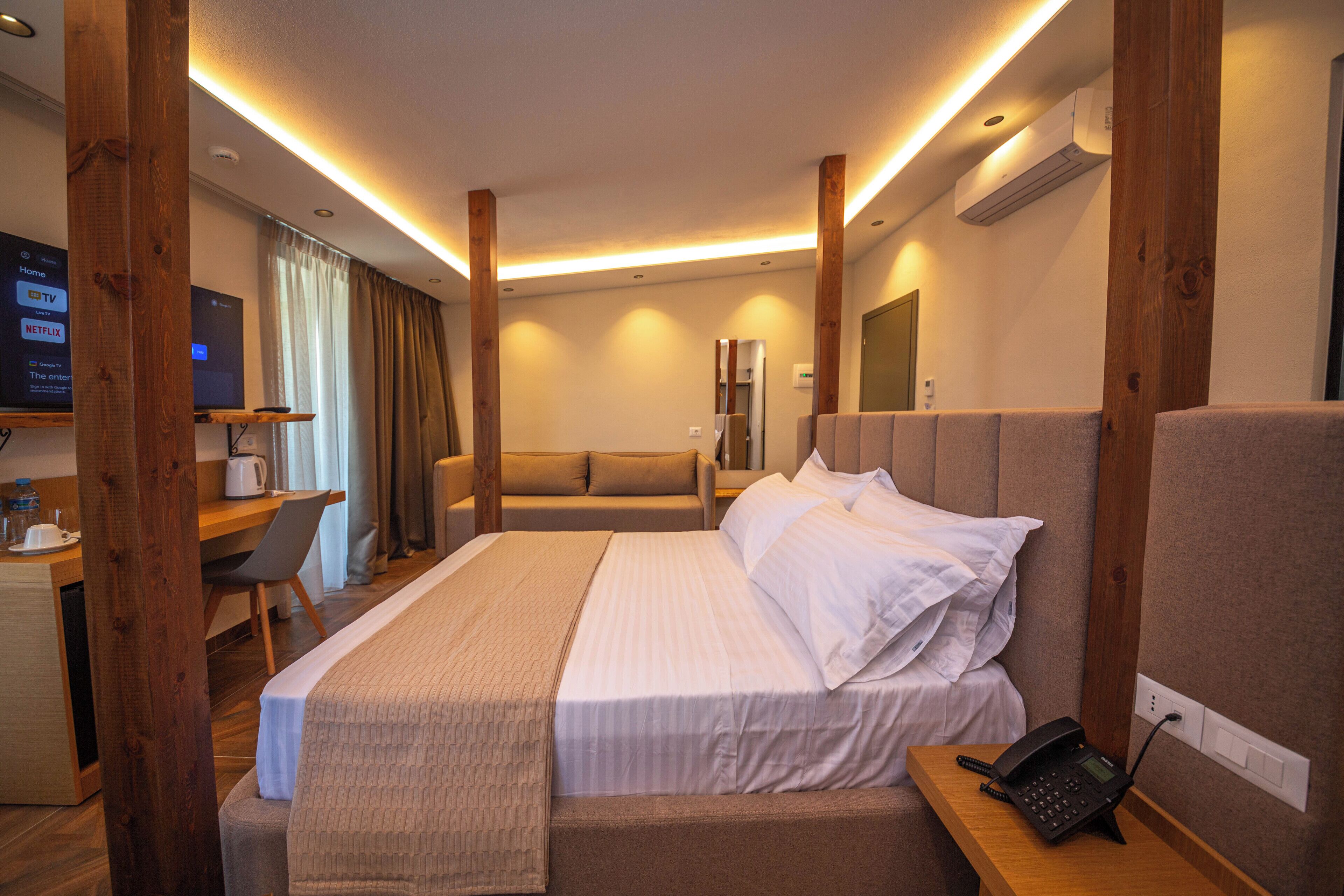 A hotel room with a bed, bedside table, and a desk with a chair.
