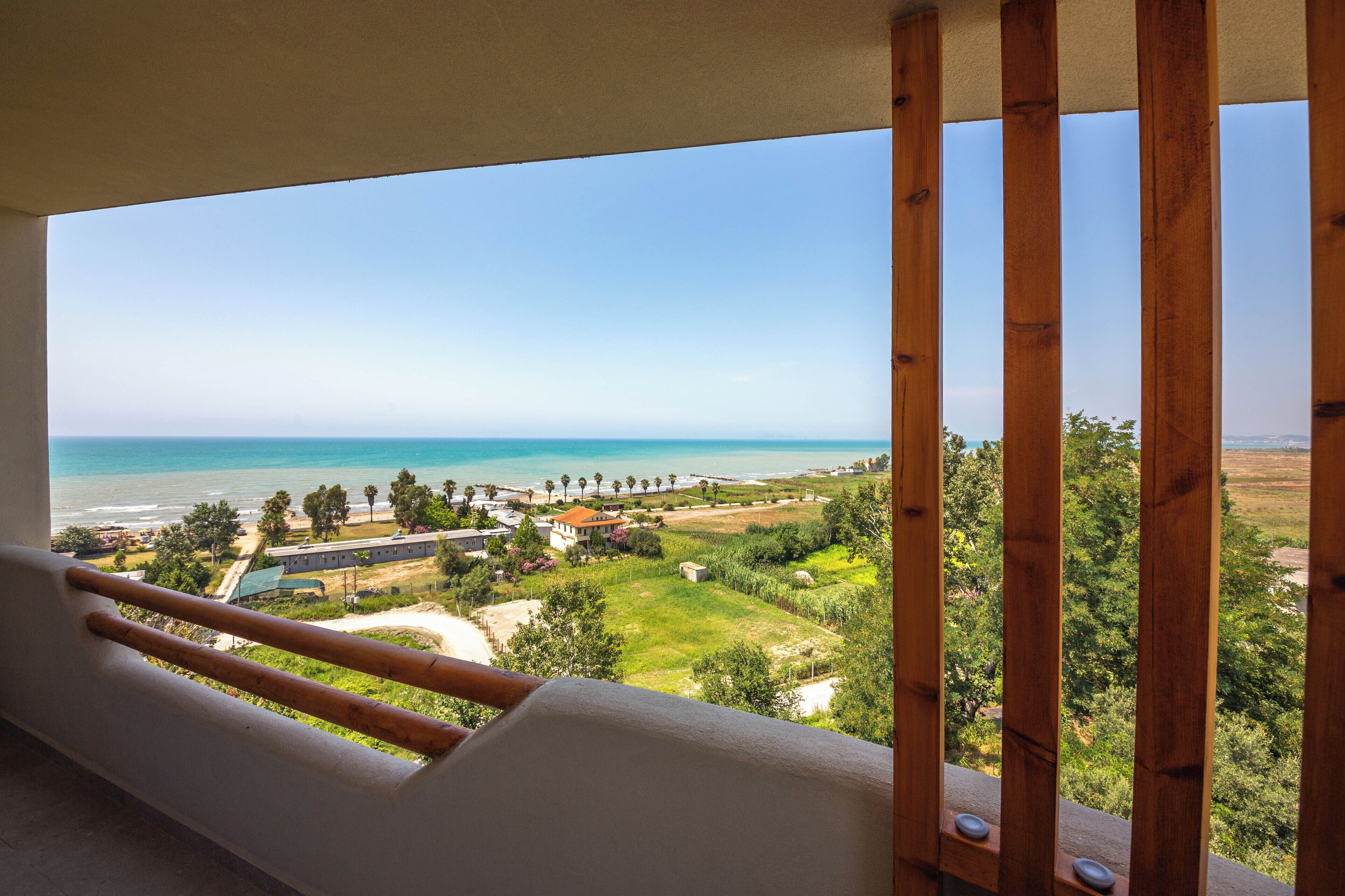 Un balcón con vistas a la playa, el océano y la vegetación circundante.