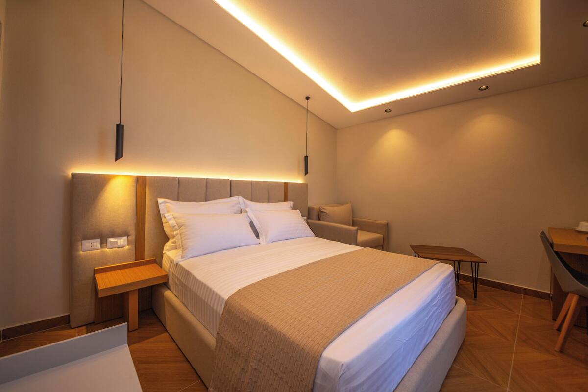 A modern hotel room with a large bed, bedside tables, a desk, and a chair.