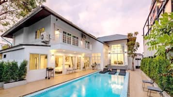 Une maison à deux étages avec une piscine, un espace extérieur aménagé et un jardin bien entretenu.