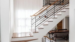 A modern staircase with wooden steps and metal railings, leading to a dining area with a wooden table and chairs. - Nimman villa 17 @Nimman soi17 (Chiang Mai)