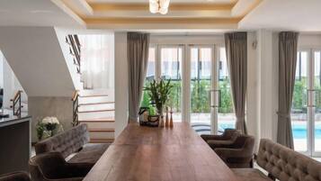 Un vaste espace dédié à la salle à manger, avec une longue table en bois, des chaises confortables et une vue sur une piscine grâce à de grandes fenêtres.
