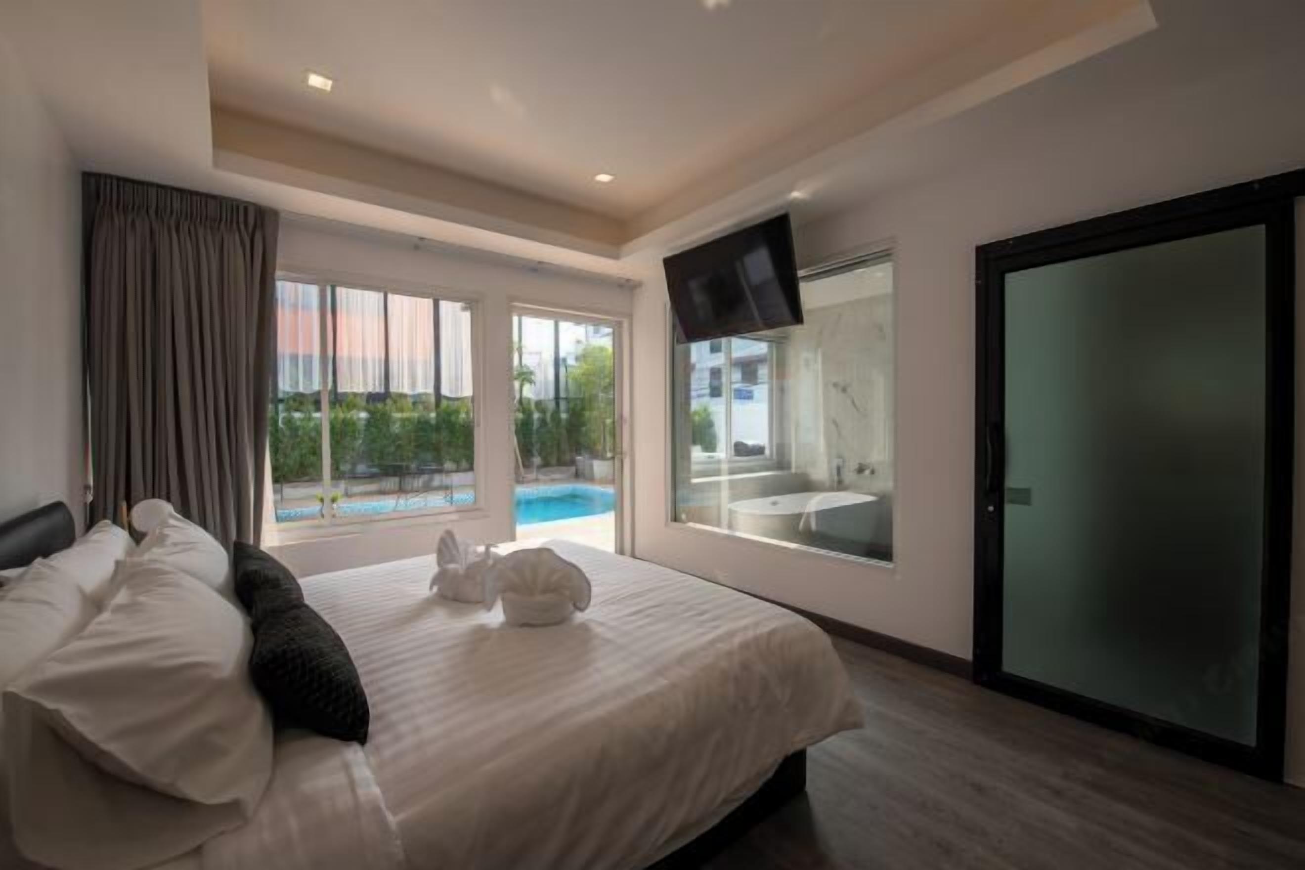 Une chambre d’hôtel avec un lit, une télévision, une grande fenêtre et une porte coulissante.