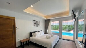 A modern hotel room with a large bed, a bench, a wooden door, and a view of a swimming pool. - Nimman villa 17 @Nimman soi17 (Chiang Mai)