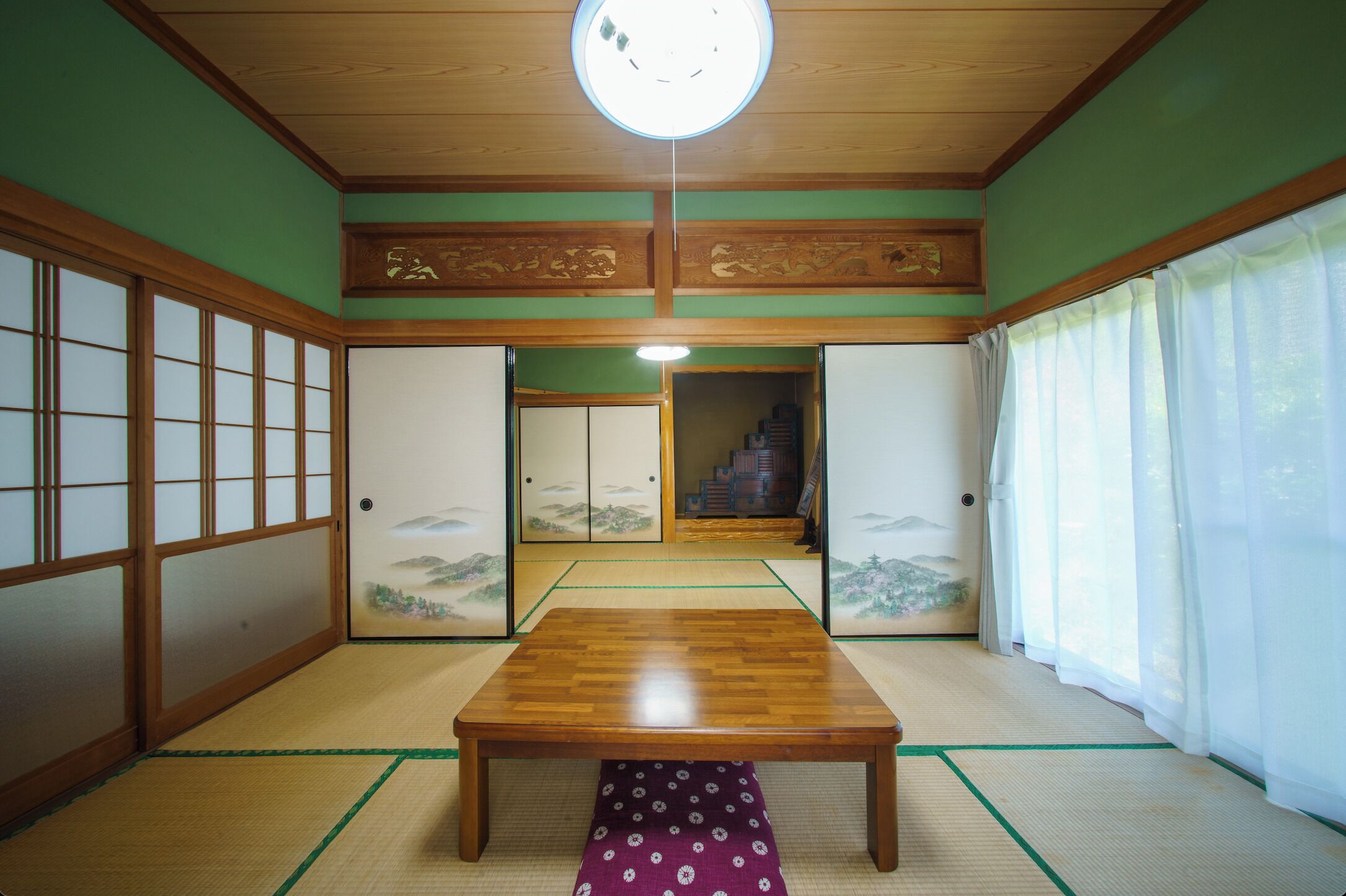 A traditional Japanese room with tatami flooring, shoji screens, and a wooden table.