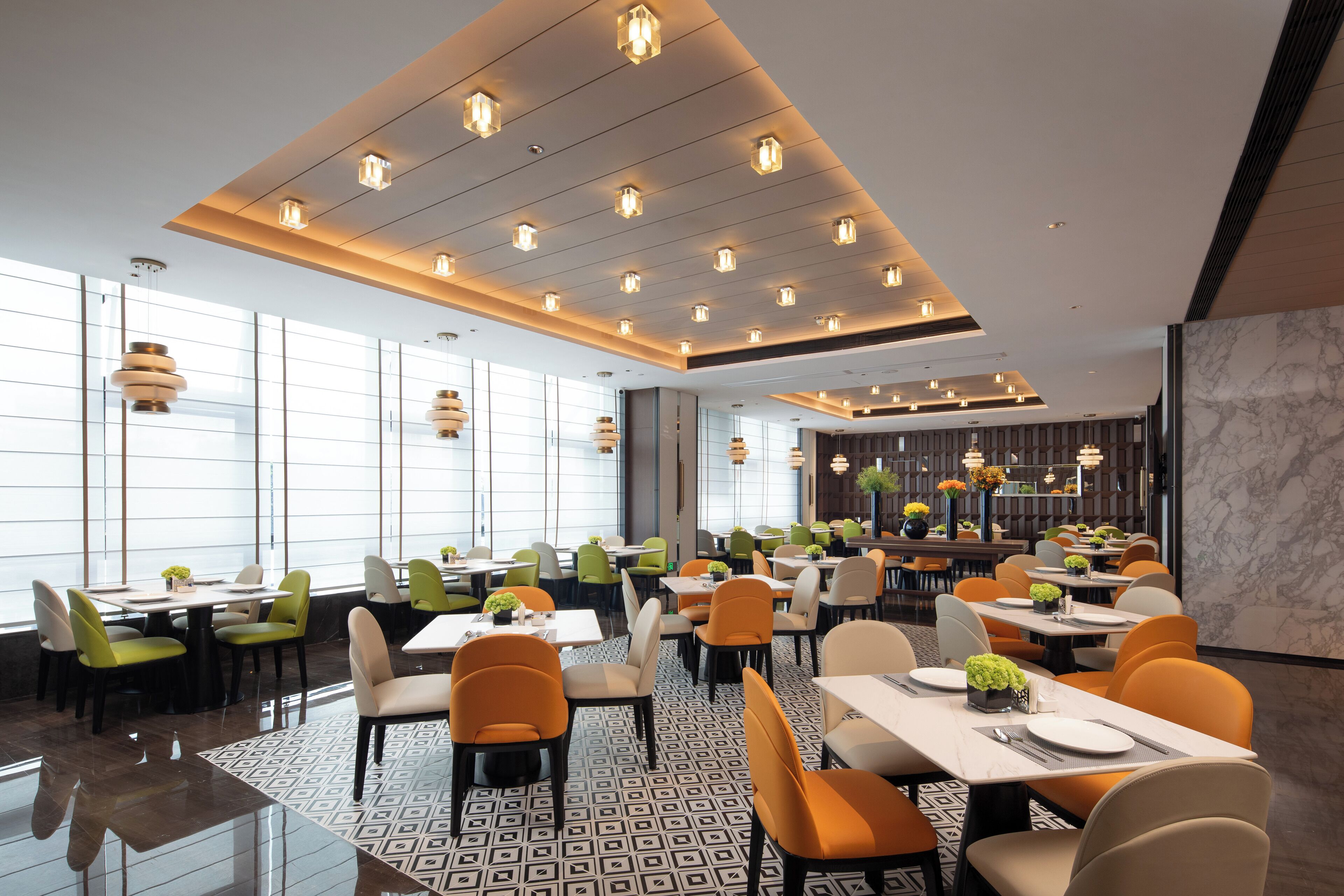 A modern restaurant with a variety of seating options, including tables and booths, and a bar area in the background.