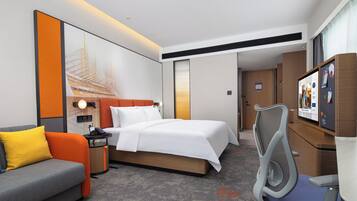 A hotel room with a bed, a sofa, a desk, and a television.