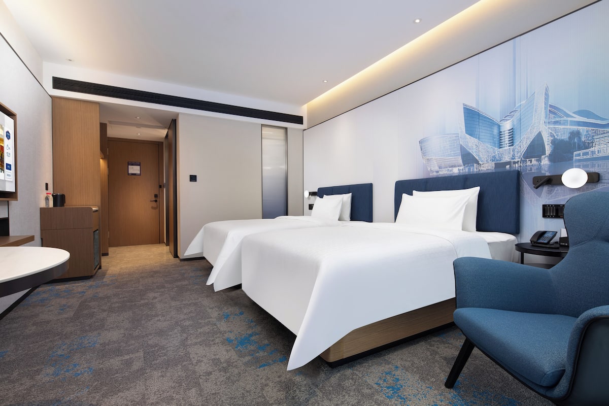 Une chambre d’hôtel avec deux lits, un bureau et une chaise.