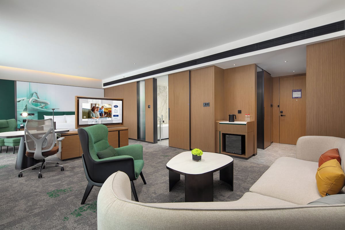 Un hall d’hôtel moderne avec un canapé, des fauteuils, une table basse, un bureau et une cheminée.