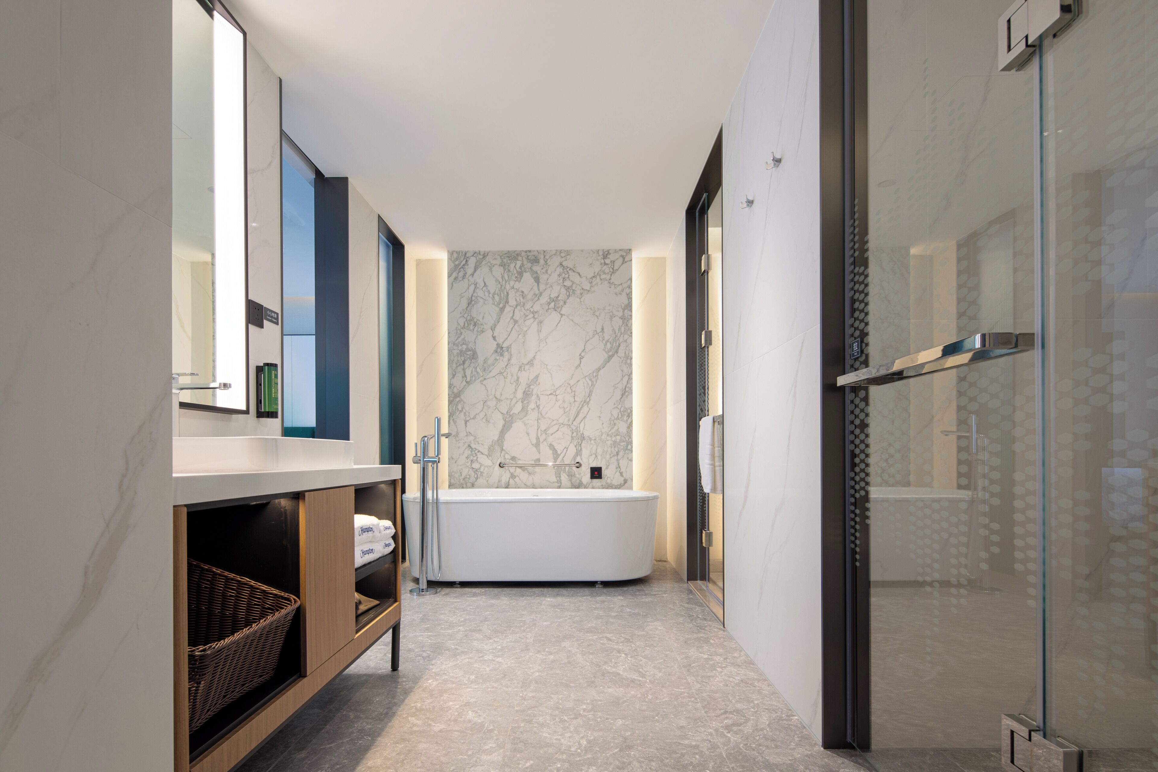 Ein modernes Badezimmer mit freistehender Badewanne, einer Glasdusche und einer Marmorwand.