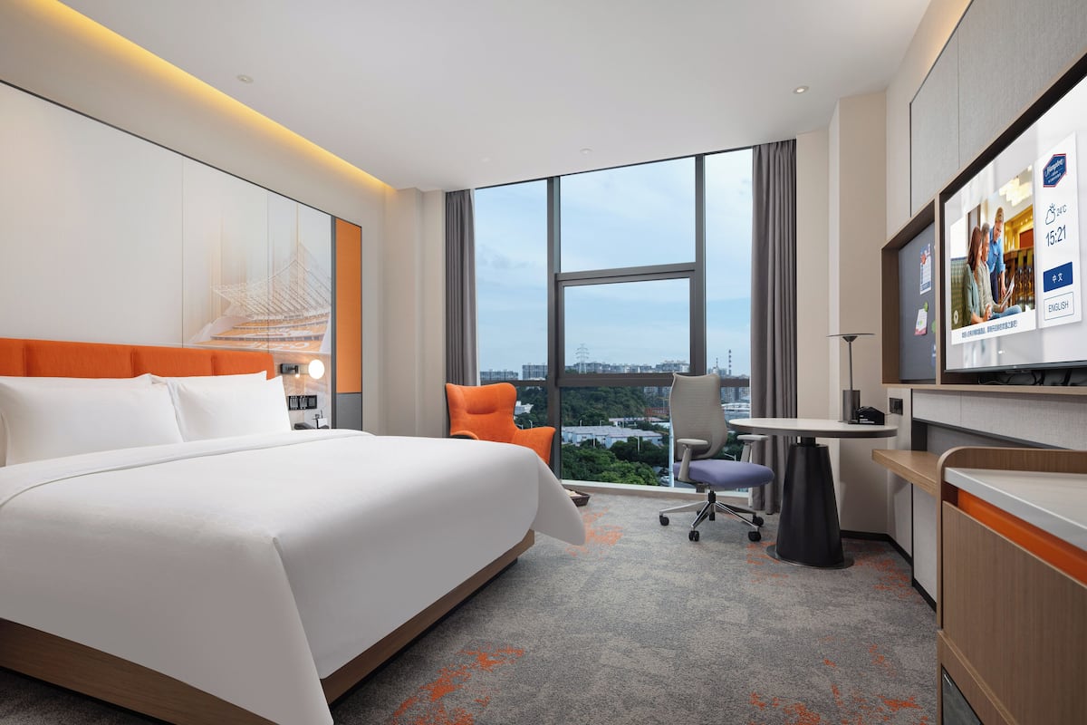 Une chambre d’hôtel avec un grand lit, un bureau, une chaise et un téléviseur.