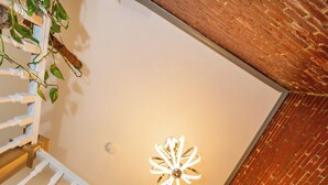 Eine Treppe mit weißen Balustern und einem hölzernen Geländer, die zu einem Raum mit Backsteinwand und einer Deckenleuchte führt.