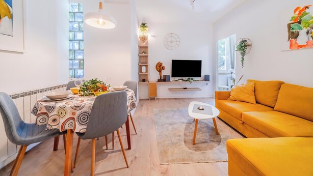 Un salon moderne comprenant un coin repas, un canapé, un téléviseur et une plante.