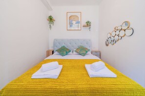 A neatly made bed with a yellow quilt, pillows, and folded towels. - Quiet Corner Central Zagreb 1BR w/ AC (Zagreb)
