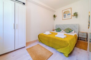 A bedroom with a bed, a wardrobe, a bedside table, and a wall-mounted plant. - Quiet Corner Central Zagreb 1BR w/ AC (Zagreb)