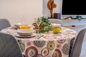 A dining table with a patterned tablecloth, various bowls, a glass, and a decorative plant. - Quiet Corner Central Zagreb 1BR w/ AC (Zagreb)