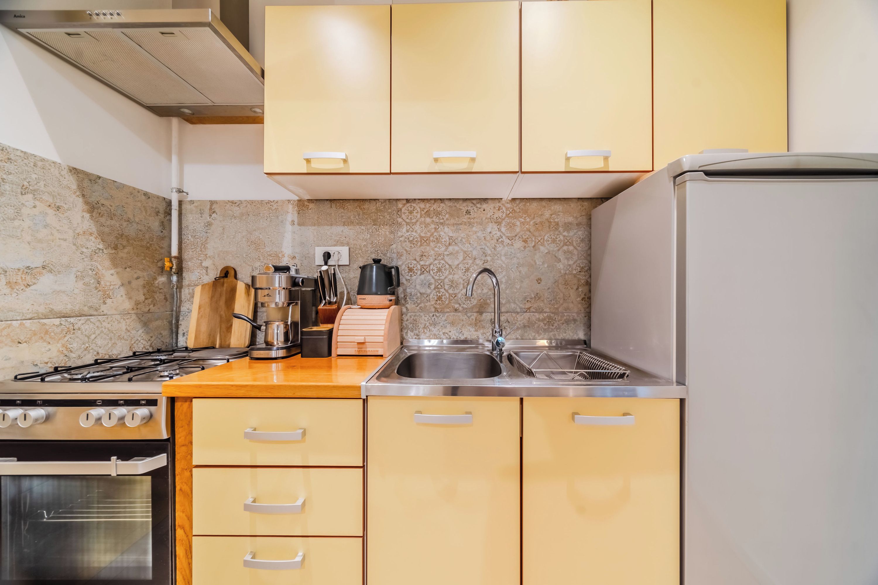 A kitchen with a gas stove, oven, sink, and cabinets.