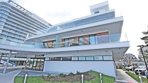 A modern building with a curved glass facade, a visible sign reading "BERLIN," and a well-maintained outdoor area with a pathway and greenery. - Baltic Park Molo by Baltic Home (Swinoujscie)
