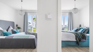 Een moderne slaapkamer met een groot bed, een nachtkastje, een lamp en uitzicht op de omgeving.