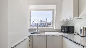 A modern kitchen with a window, a sink, a microwave, and a kettle. - Covent Garden’s Secret, by Veeve (London)