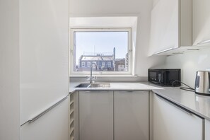 Una cocina moderna con ventana, un lavamanos, un microondas y un hervidor.