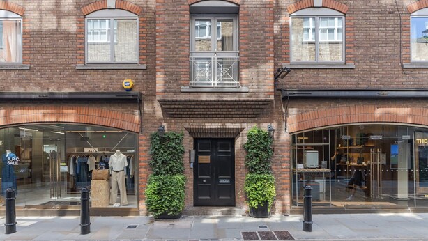 A brick building with two storefronts, one with a sale sign and mannequins, and the other with a visible interior. - Covent Garden’s Secret, by Veeve (London)