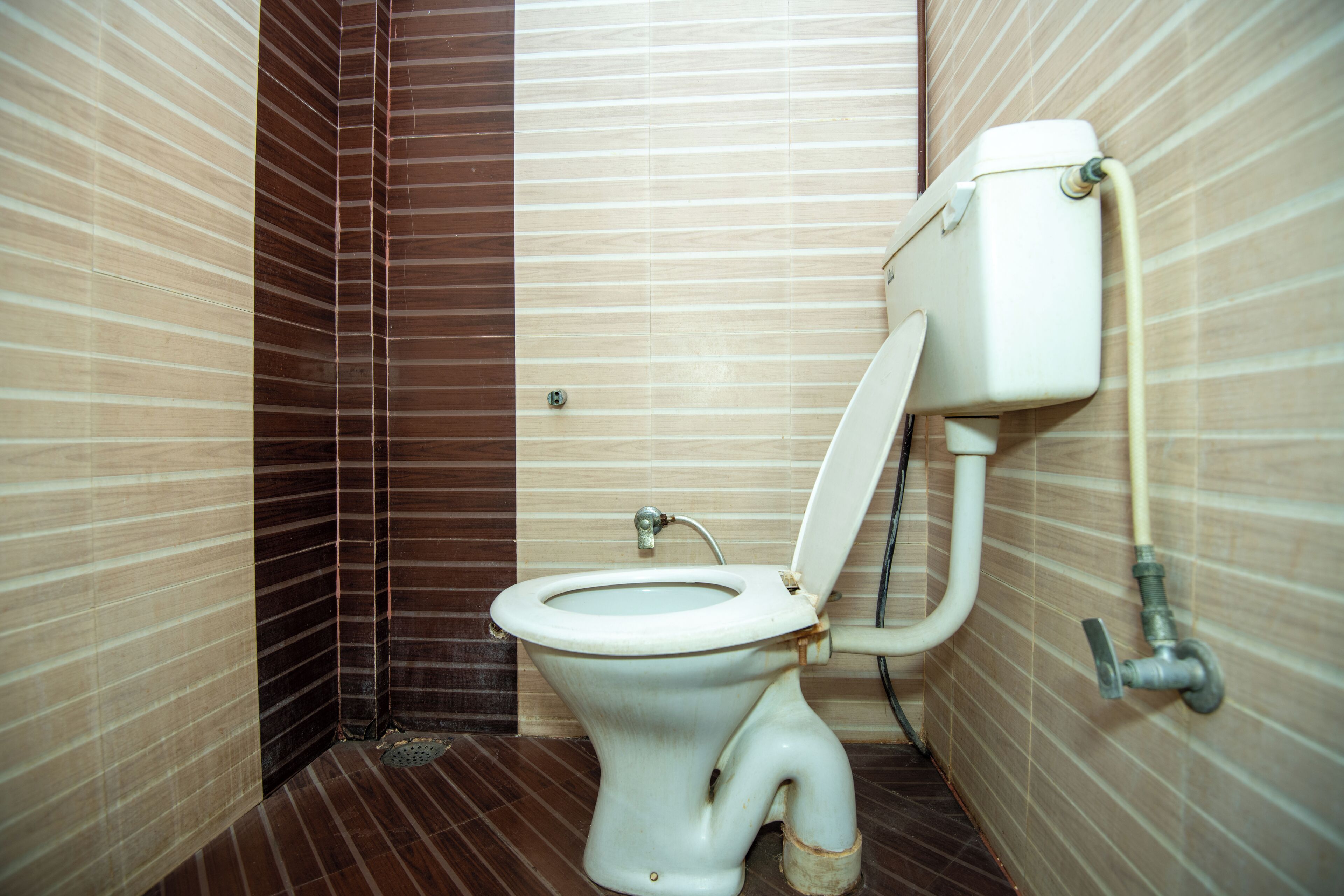 A small, narrow bathroom with a toilet, a wall-mounted sink, and a tiled floor.