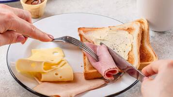 Une assiette avec des tranches de fromage, de jambon et du beurre sur des toasts.