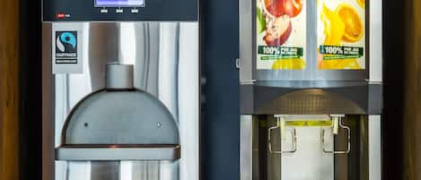 To kaffemaskiner med digitale skærme og frugt-motiver.