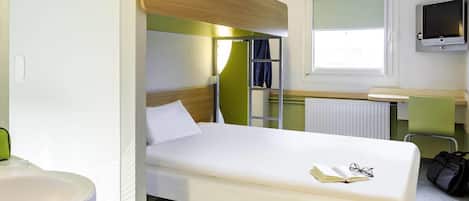 A single-bed room with a bunk bed, a small desk, a TV, and a window.