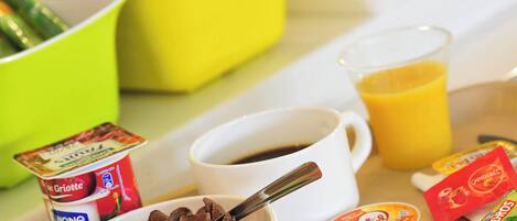 A breakfast tray with cereal, coffee, juice, and yogurt.
