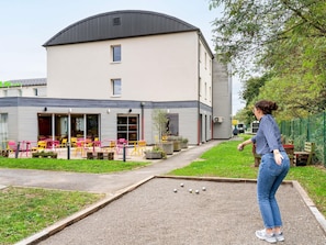 Un edificio con techo plano, un patio con mobiliario exterior y un jardín.