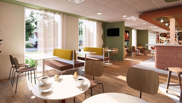 Una cafetería moderna con mesas y sillas redondas, un televisor montado en la pared y amplios ventanales que ofrecen vistas al exterior.