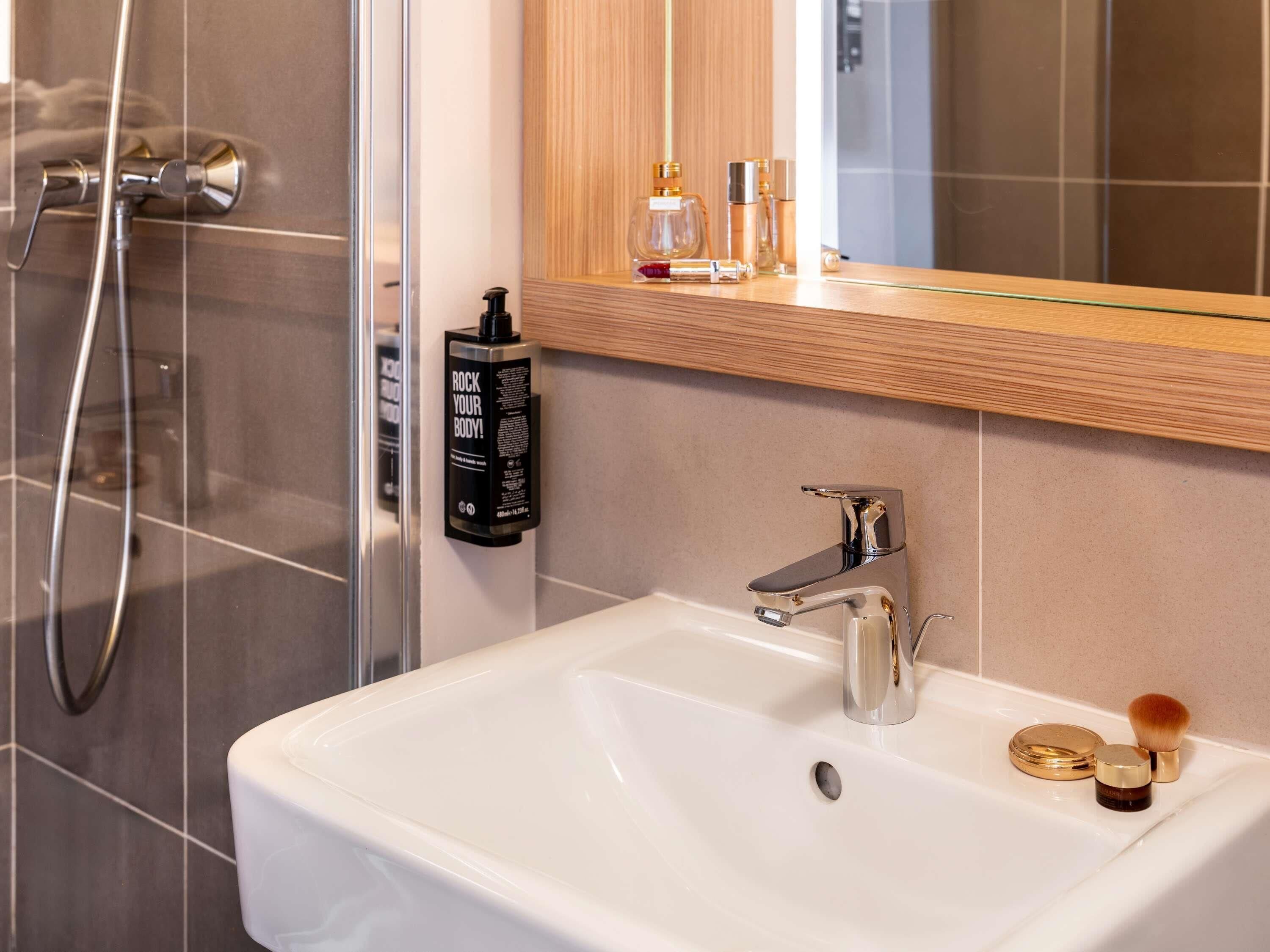 A modern bathroom with a white sink, chrome faucet, and a handheld showerhead.