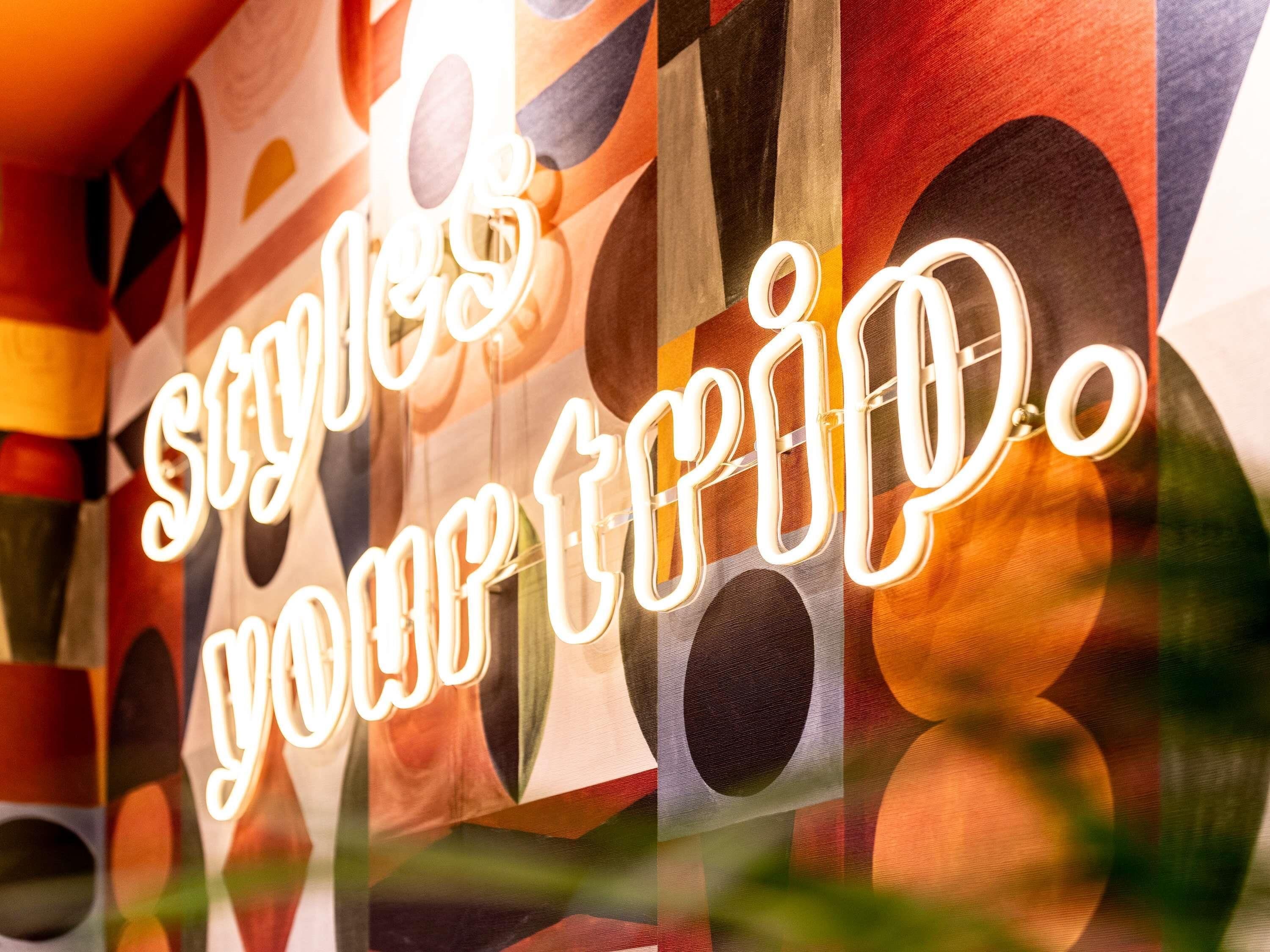 A neon sign with the text 'styles your trip.'